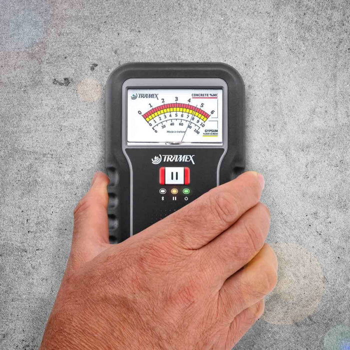 Tramex CME5 - Concrete Moisture Encounter CME5; an image showing the Tramex CME5 moisture meter being held in a hand while resting on a concrete floor, illustrating its use in measuring moisture levels in concrete surfaces.
