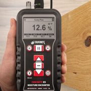 Tramex Flooring Inspector EZ Kit - FZK: An image showing the Tramex CMEX5 moisture meter with a pin probe, placed on wooden flooring for moisture inspection. The device features a digital display and is designed for assessing moisture content in various flooring materials.