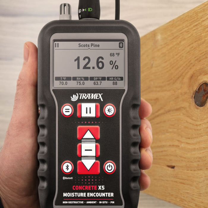 Tramex Flooring Inspector EZ Kit - FZK: An image showing the Tramex CMEX5 moisture meter with a pin probe, placed on wooden flooring for moisture inspection. The device features a digital display and is designed for assessing moisture content in various flooring materials.