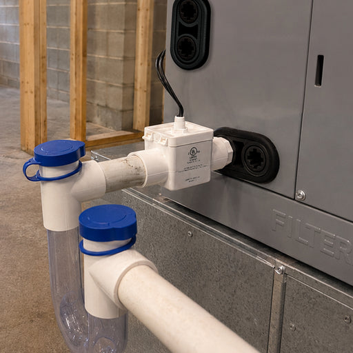 Wider view of the installed CoolGuard trap kit: switch tank, capped tees and clear U trap below the air handler