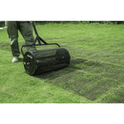 Dapper Supply compost spreader rolling over freshly top-dressed turf in a yard.