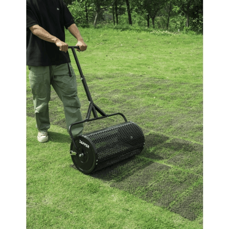 Dapper Supply compost spreader spreading material evenly across a backyard lawn.
