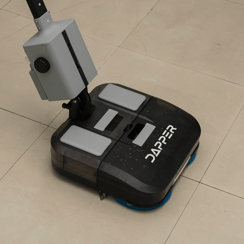 Dapper Supply 16-inch battery walk-behind floor scrubber cleaning a wood floor.