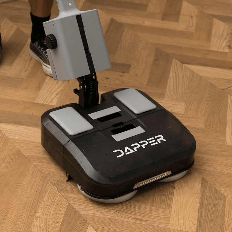 Dapper Supply 16-inch battery walk-behind floor scrubber top deck detail on wood floor.