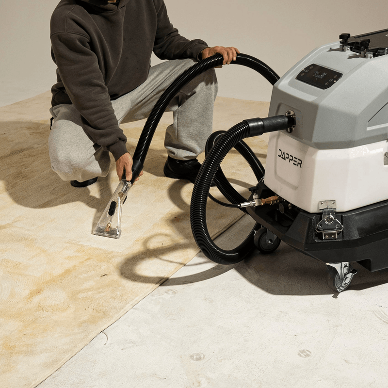 Dapper Supply heated carpet extractor in use with the upholstery tool on a carpeted floor.
