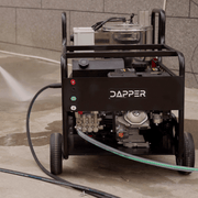 Dapper Supply hot water gas pressure washer in use spraying on a concrete surface.