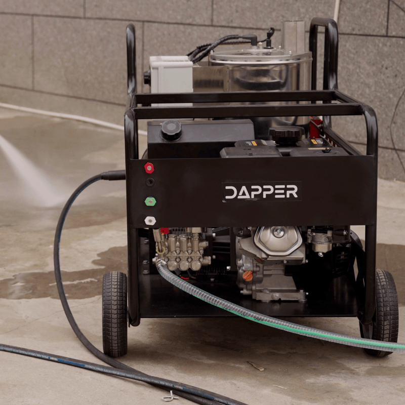 Dapper Supply hot water gas pressure washer in use spraying on a concrete surface.