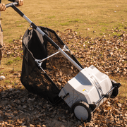 Dapper Supply push lawn sweeper collecting leaves on a lawn.