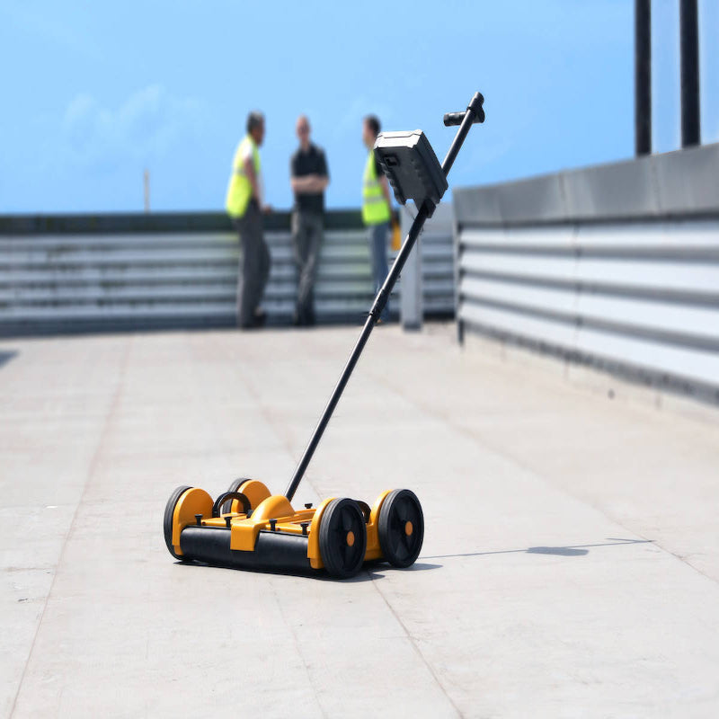 Tramex DS2 - Dec Scanner: Image showing the Tramex DS2 moisture scanner in action on a roof, with people in the background engaged in work.