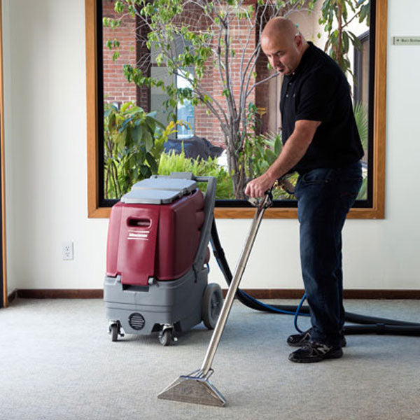 Minuteman Rush carpet extractor in use with a stainless steel floor wand on office carpet