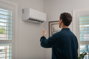 DIY Select air handler on a living room wall being operated with its handheld remote