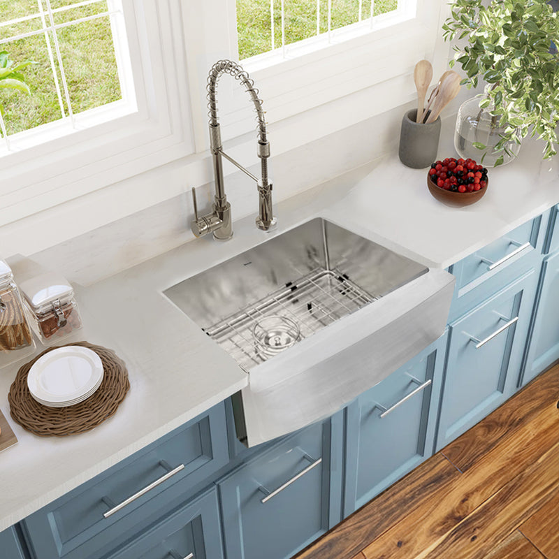 Nantucket Sinks APRON2420-SR-16 installed in a white counter over blue cabinets, grid in the bowl