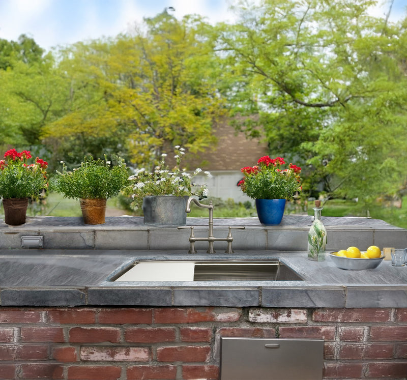 Nantucket Sinks AW-PS-3219-16 installed in a stone outdoor counter on a brick base in a garden