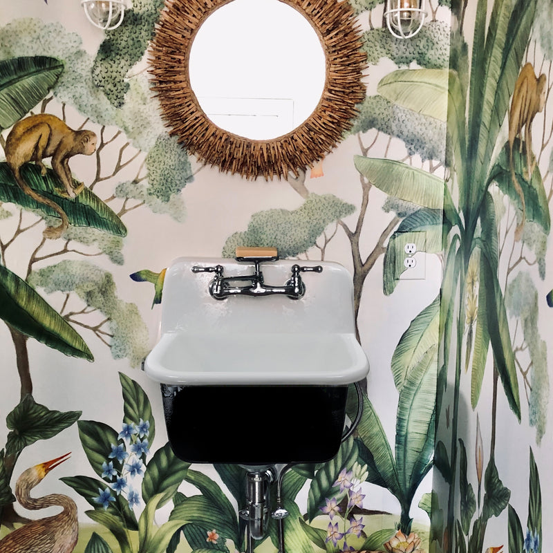 Nantucket Sinks CI-2218WNRG utility sink wall-mounted against tropical wallpaper under a round mirror