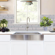 Nantucket Sinks EZApron33-5.5 installed under a window in a white kitchen with subway tile