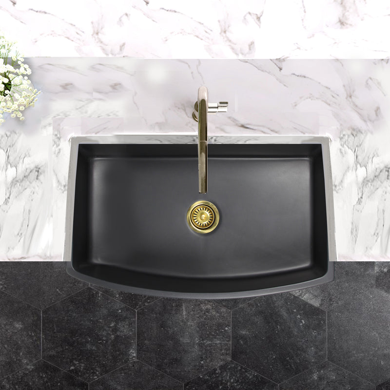 Nantucket Sinks FCFS3320CA-MB Matte Black curved apron sink from above in a marble counter with brass drain
