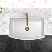 Nantucket Sinks FCFS3320CA-W white curved apron sink from above in a marble counter with brass faucet