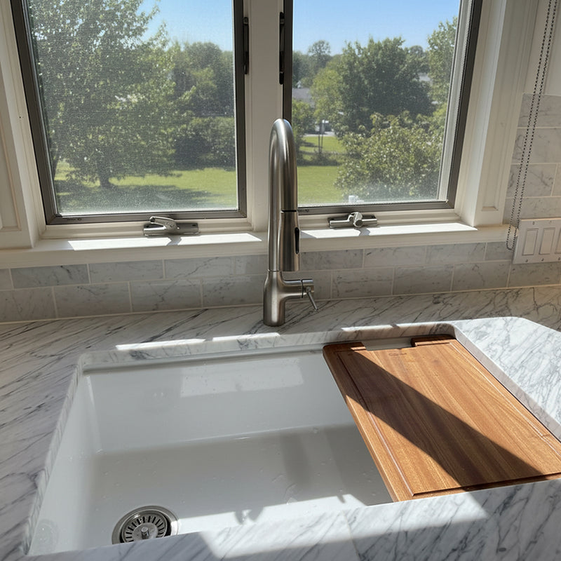Nantucket Sinks KFPD16BRS brushed stainless faucet behind a white fireclay sink with wood board