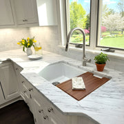 Nantucket Sinks KFPD16BRS brushed stainless faucet over a white sink with a wood board on marble