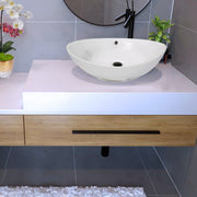 Nantucket Sinks NS-UDMB-OF matte black drain in a white oval vessel sink with overflow hole on a white vanity