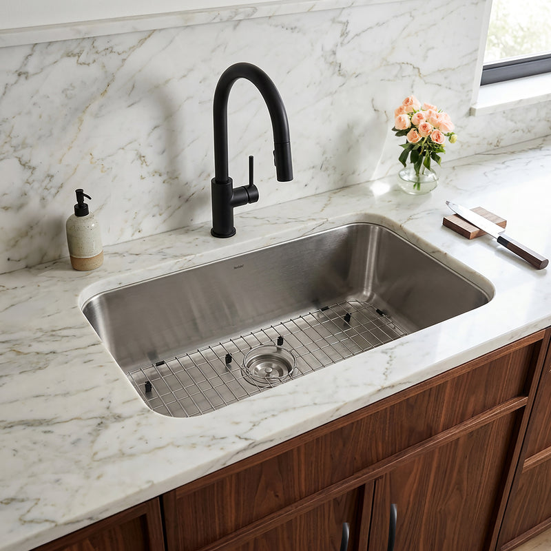 Nantucket Sinks NS3018-9-16 installed in white marble with a black faucet and grid