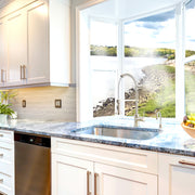 Nantucket Sinks NS3018-9-16 installed in a blue granite counter under a window with a water view