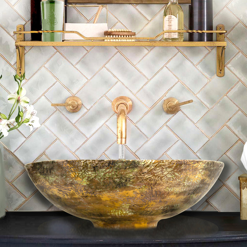 Nantucket Sinks RC7040GMS-W Drake gold leaf vessel sink below a brass wall faucet and tiled wall