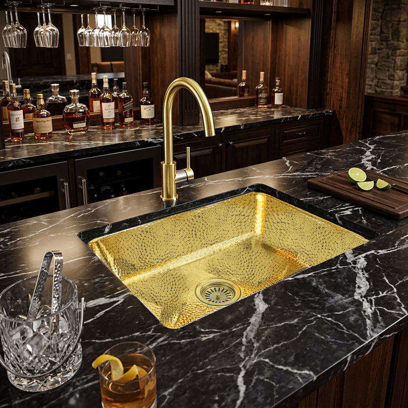 Nantucket Sinks REB2014 hammered brass sink in a black marble home bar with a brass faucet and glassware