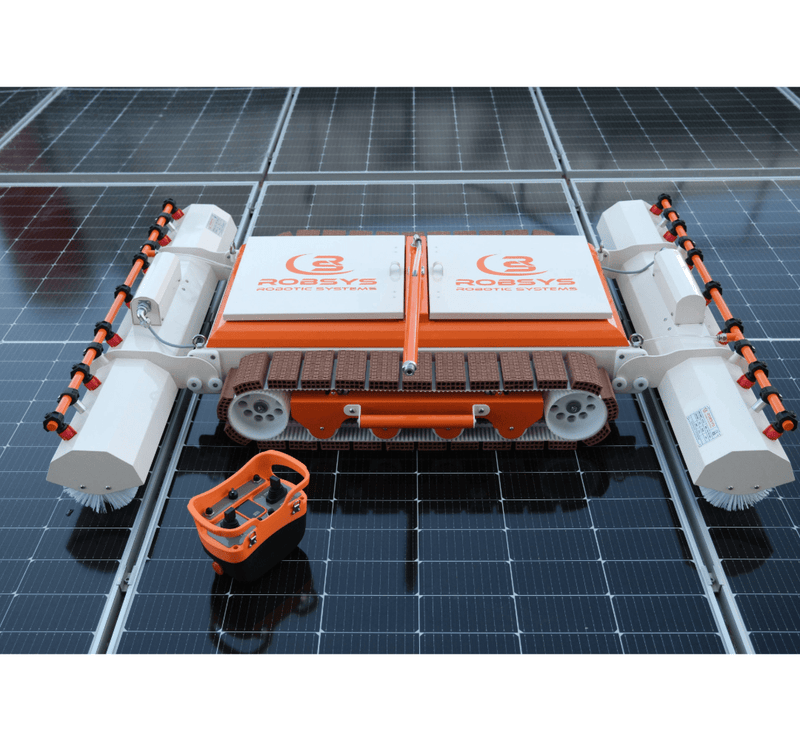 Tucker RTM PRO solar cleaning robot on solar panels with its orange handheld remote