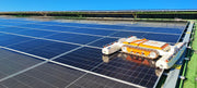 Tucker RTM solar panel cleaning robot working across a row of solar panels under blue sky