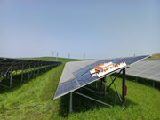 Tucker RTM solar cleaning robot on a tilted solar panel table in a grassy field
